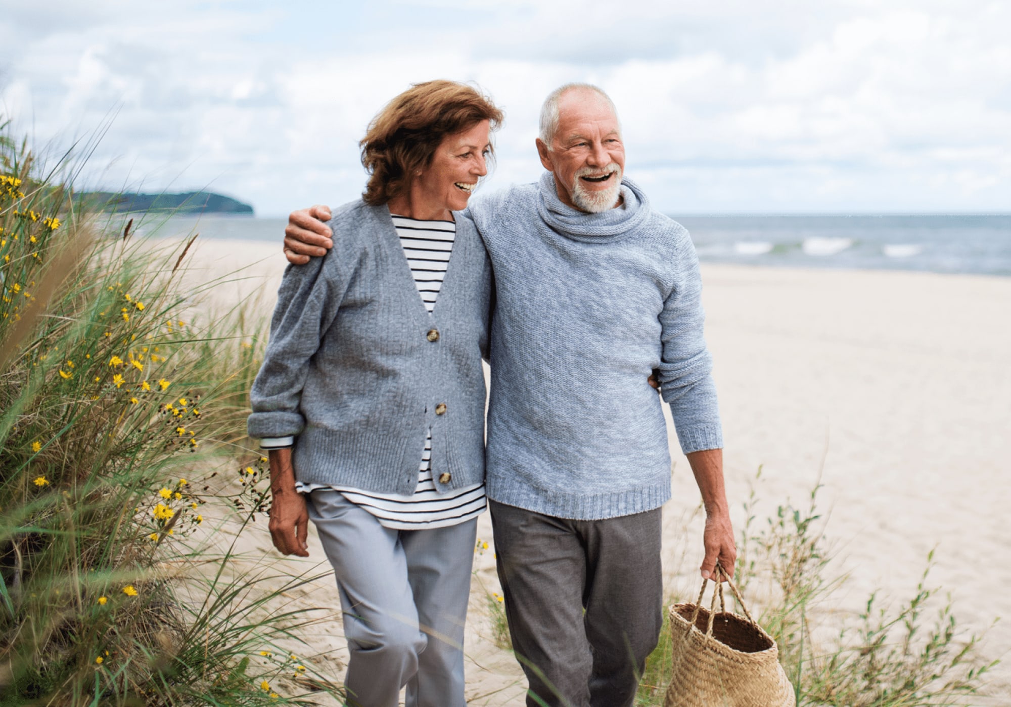 Elderly couple hugging and walking on the beach