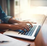 Hands typing on a laptop