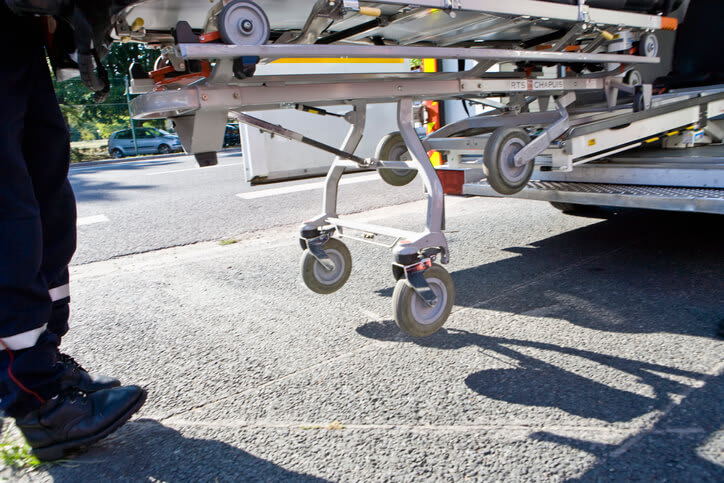 A view of the bottom of a medical gurney being loaded into the back of an ambulance