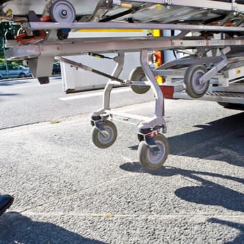 A view of the bottom of a medical gurney being loaded into the back of an ambulance