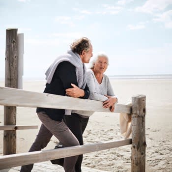 Retired couple leaning on a fence at the beach