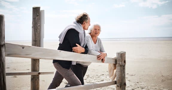 Retired couple leaning on a fence at the beach