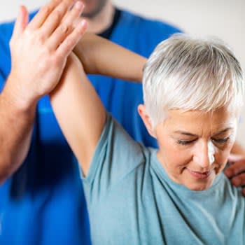 A chiropractor pulls a woman's arm back in a stretch