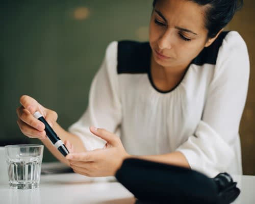 Woman uses pen to prick finger to test blood sugar