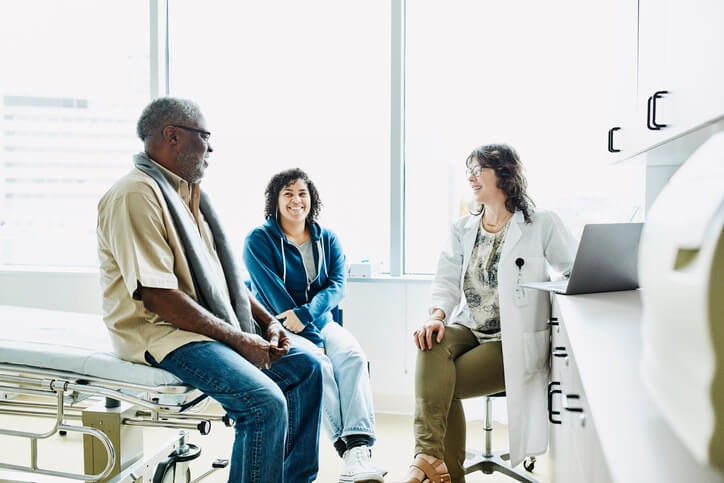 Doctor speaks with smiling couple in doctor's office