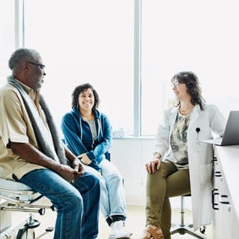 Doctor speaks with smiling couple in doctor's office