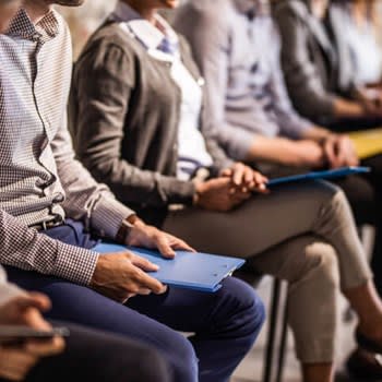 People sitting with resumes and waiting in line for job interviews