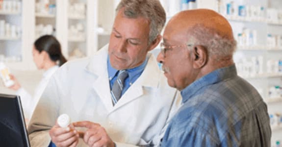 Pharmacist points to information on prescription bottle for patient