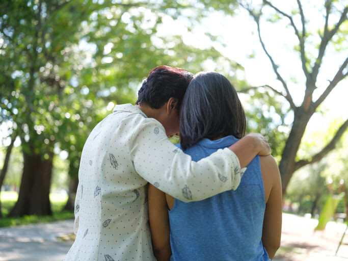 Rear view of two women comforting each other with embrace