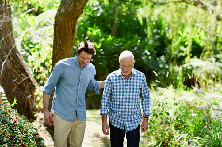 Man walks through outdoor park with caregiver