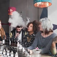 A group of young adults vaping and using e-cigarettes in a vape store