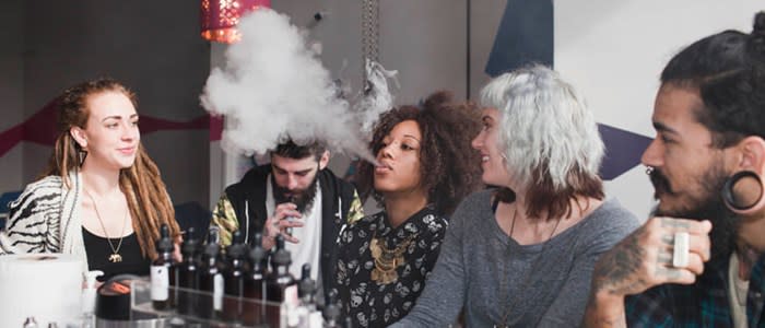 A group of young adults vaping and using e-cigarettes in a vape store