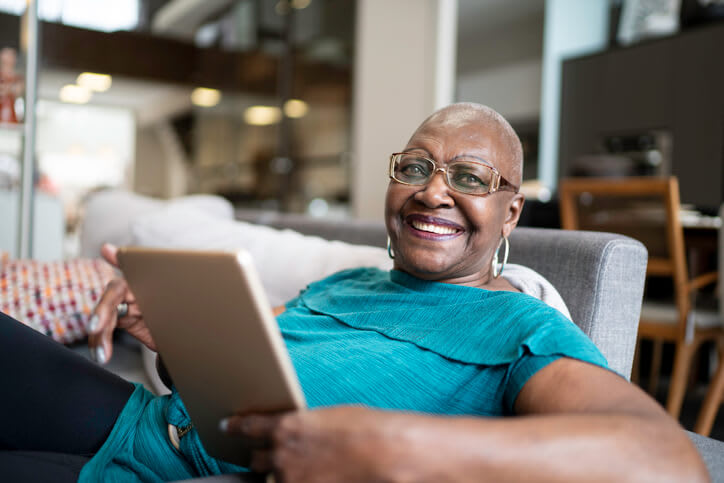 Happy woman smiles while using tablet at home