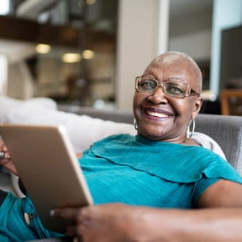 Happy woman smiles while using tablet at home