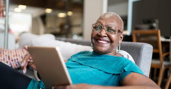 Happy woman smiles while using tablet at home