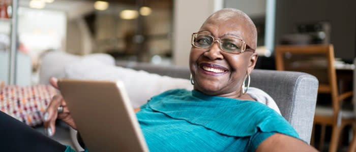 Happy woman smiles while using tablet at home