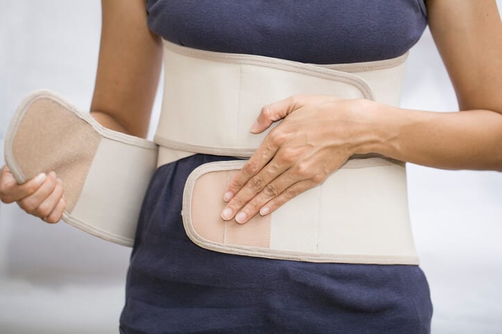 Front view of woman buckling a back brace