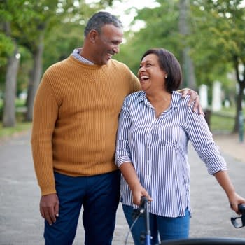 Couple smiles and uses walker outside