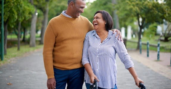 Couple smiles and uses walker outside