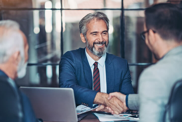 Man smiles and shakes hands with potential employer job interviewer