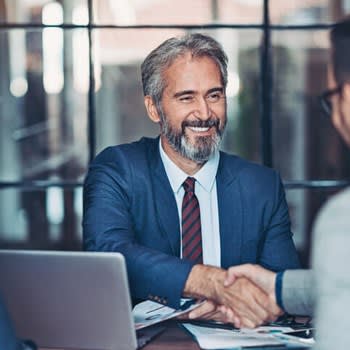 Man smiles and shakes hands with potential employer job interviewer