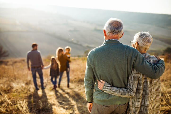 Grandparents Embrace And Gaze At Family