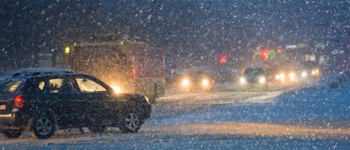 A snowy night scene with car headlights