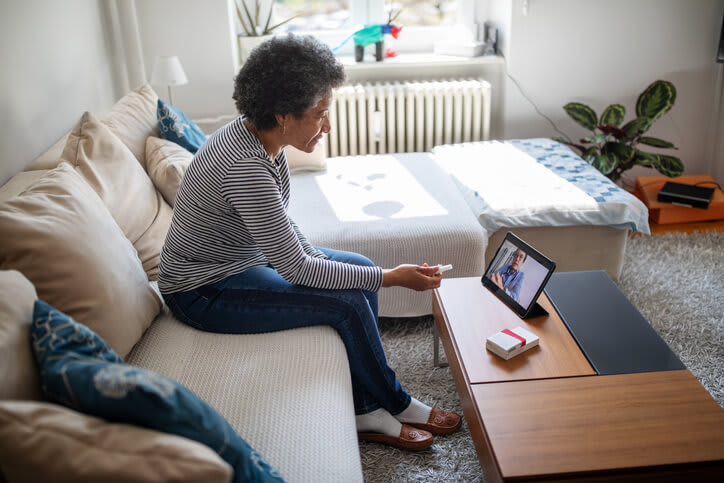 Woman at home speaks with doctor using telemedicine