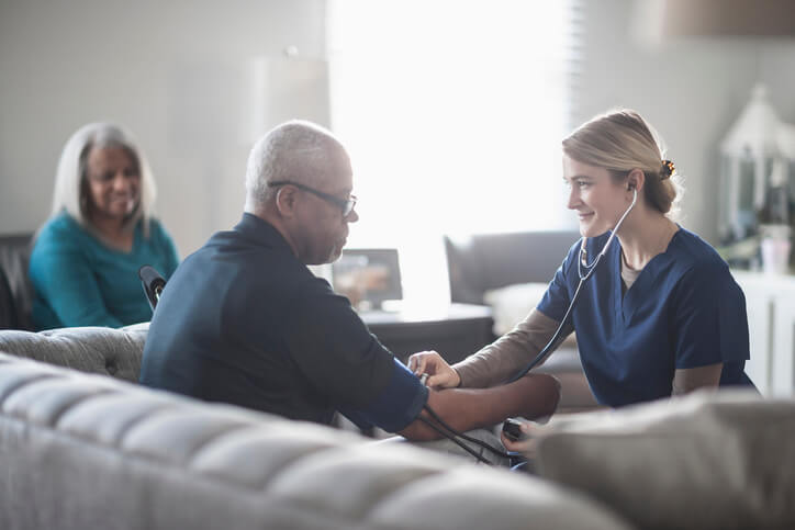 Home health nurse measures patient's blood pressure