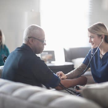 Home health nurse measures patient's blood pressure