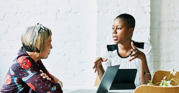 Two women chat while one uses her laptop computer