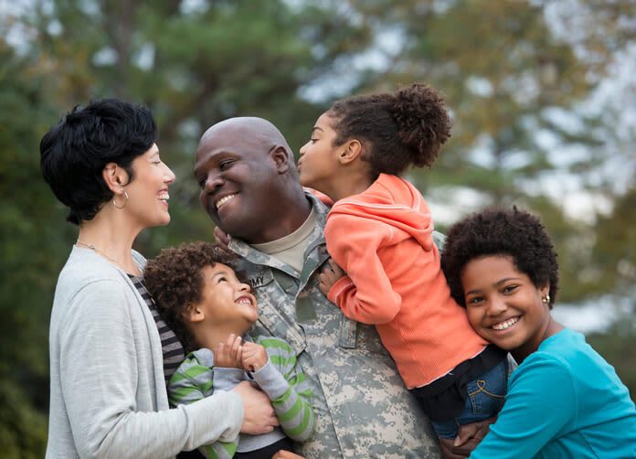 Veteran father smiles and embraces his children