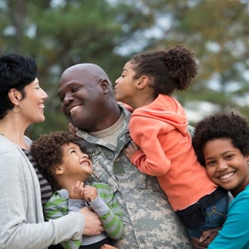 Veteran father smiles and embraces his children