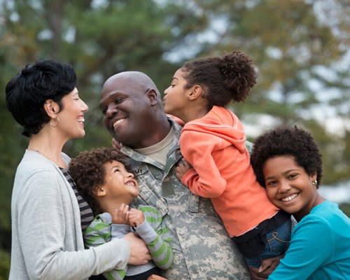 Veteran father smiles and embraces his children