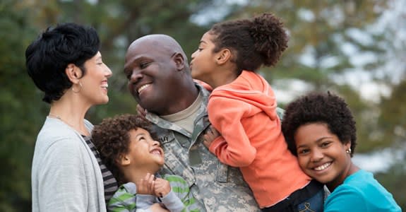 Veteran father smiles and embraces his children