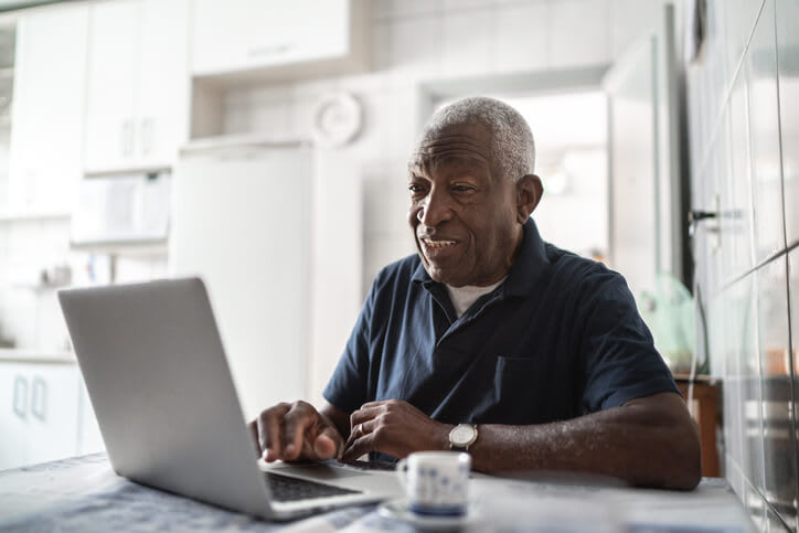 Man uses laptop computer at home in his kitchen