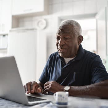 Man uses laptop computer at home in his kitchen