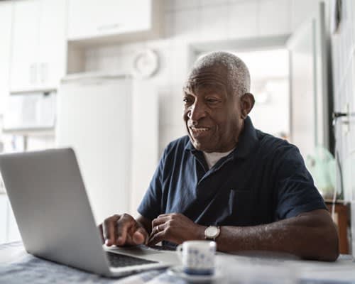 Man uses laptop computer at home in his kitchen