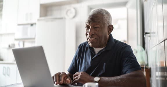 Man uses laptop computer at home in his kitchen