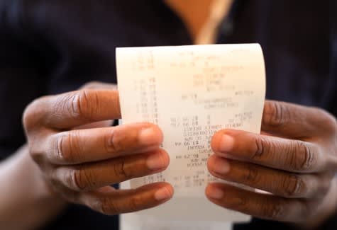 Two hands holding a receipt showing grocery prices