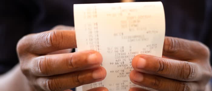 Two hands holding a receipt showing grocery prices