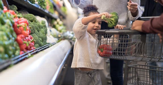 Girl Puts Produce In Grocery Cart