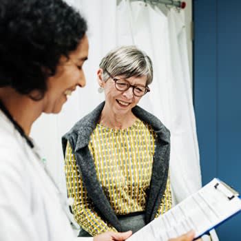 Smiling doctor reviews medical information with happy patient