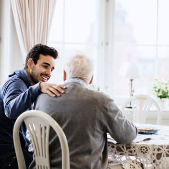 Caregiver comforts older man in his home