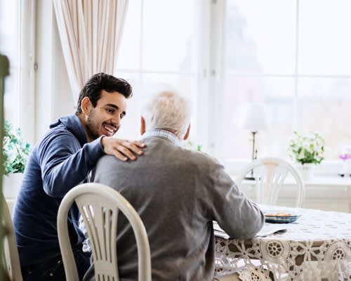 Caregiver comforts older man in his home