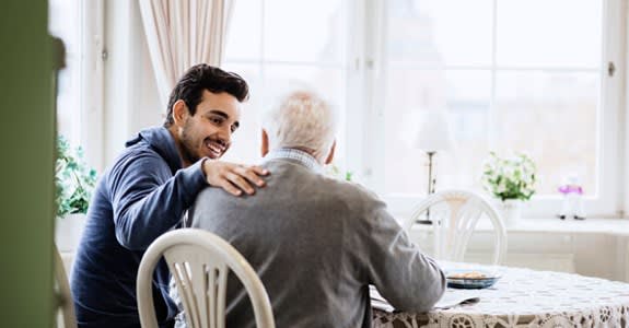 Caregiver comforts older man in his home