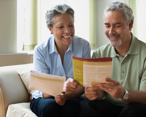 Smiling couple at home reviewing insurance information