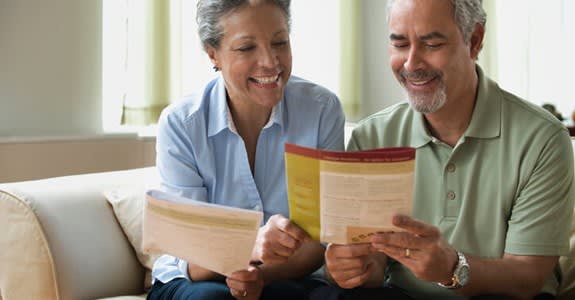 Smiling couple at home reviewing insurance information