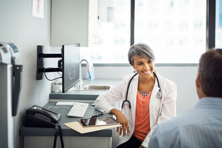 A doctor smiles and speaks with her patient