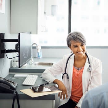 A doctor smiles and speaks with her patient